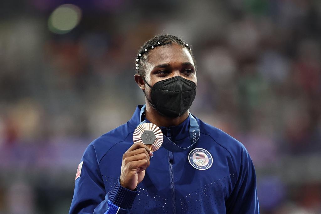 Noah Lyles poses with his bronze medal while wearing a mask after finishing third in the 200-meter final at the Olympics on Aug. 8, 2024.