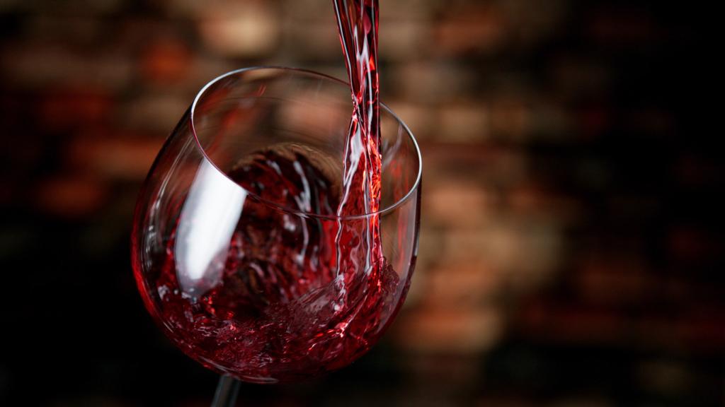 Freeze motion of red wine being poured into a glass in an old cellar interior