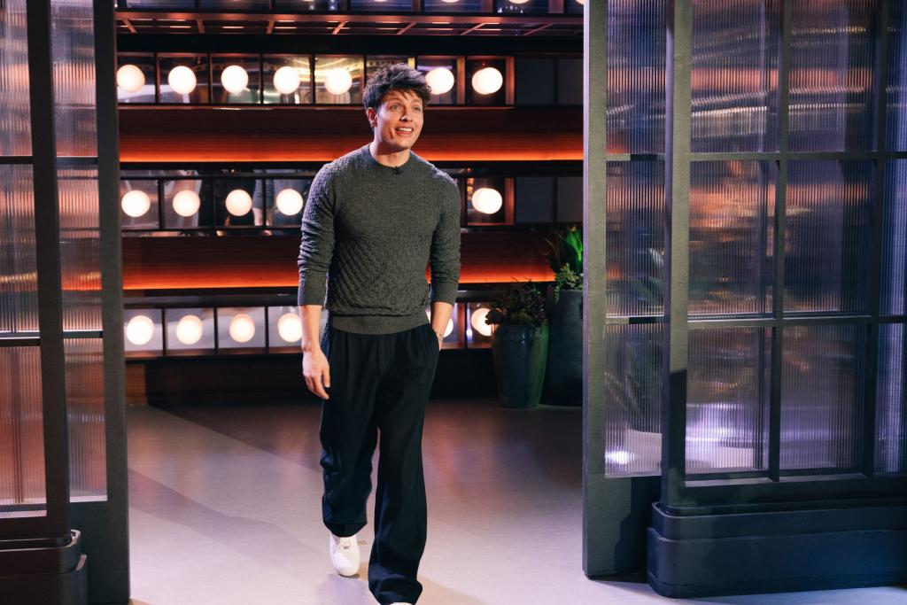 Matt Rife walking onto a stage, smiling. 