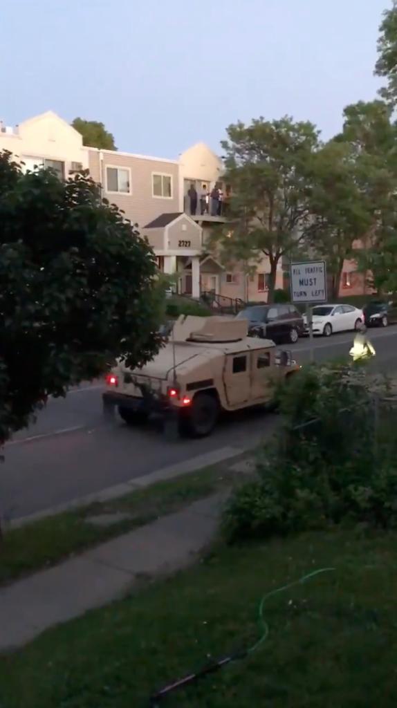 Tan army Humvee rolls down the street