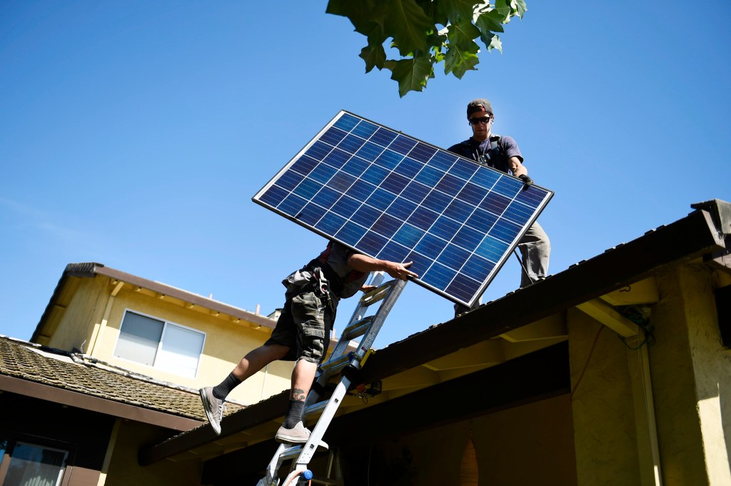 SunRun installers Brandon Anderson and Will LaRocque prepare to install one of 28 Q-Cell panels on a home on Friday, July 15, 2016 in Sunnyvale, California