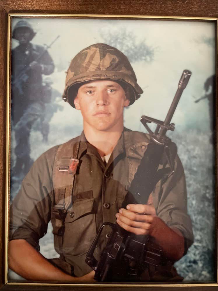 Tim Walz in uniform, holding a rifle