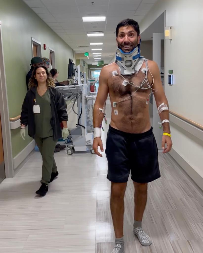 Nev Schulman walking in the hospital with his neck brace on