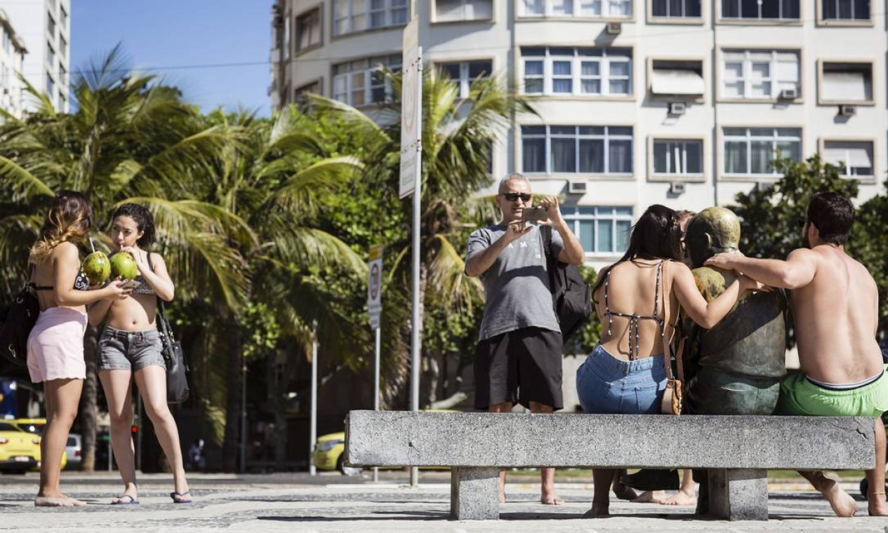 O poeta é pop: turistas batem foto ao lado da estátua de Carlos Drummond de Andrade, em Copacabana, na altura do Posto 6. O par de óculos do mineiro, infelizmente, já foi roubado algumas vezes. Foto: Fernando Lemos / Agência O Globo