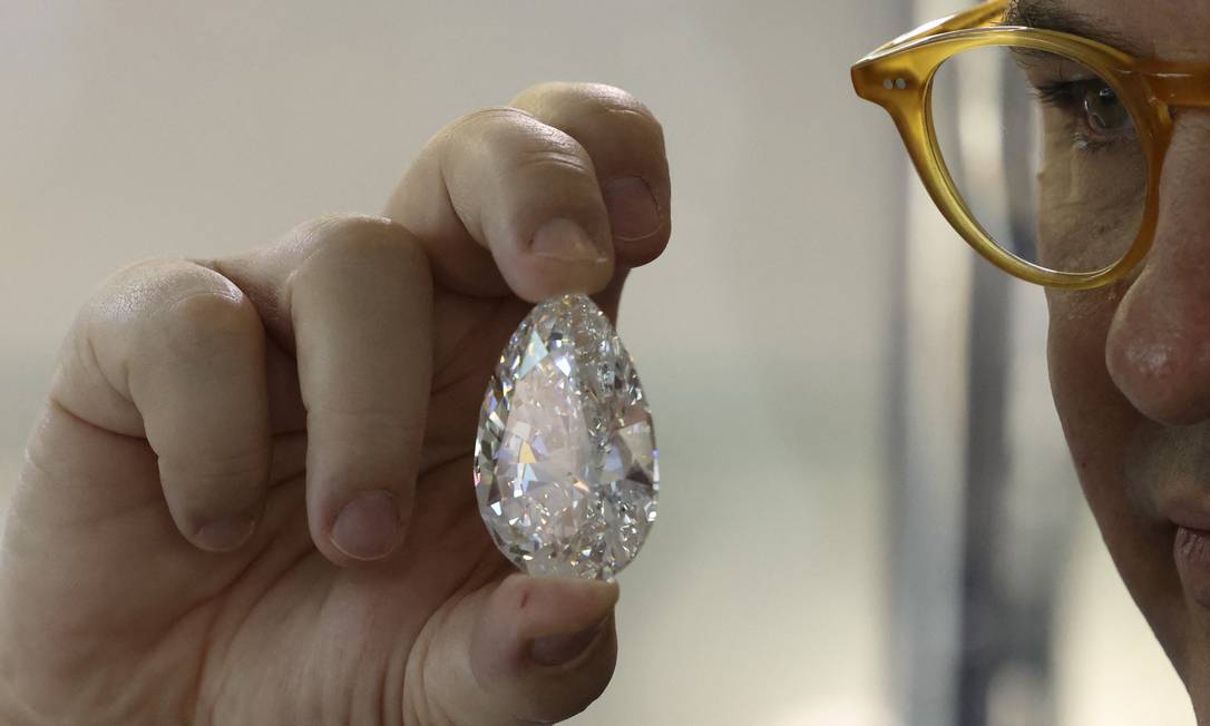 Funcionário da casa de leilões Christie's exibe o diamante, chamado de "The Rock", que tem 228,31 e é o maior do tipo pera e tons de branco já catalogado Foto: KARIM SAHIB / AFP