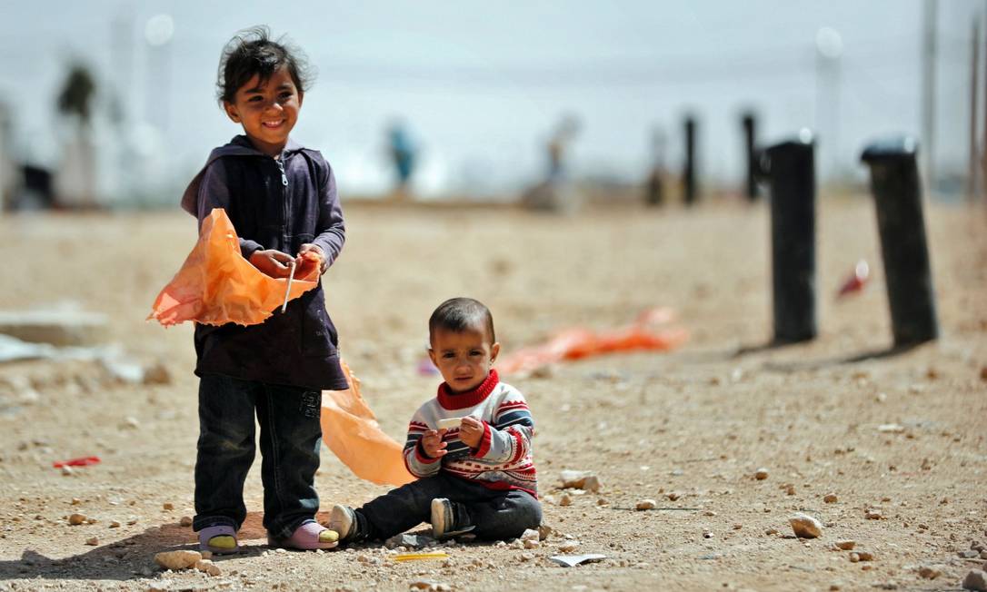 Pequenos refugiados sírios olham para a câmera em campo que abriga 80 mil pessoas na fronteira entre Jordânia e Síria Foto: THOMAS COEX / AFP