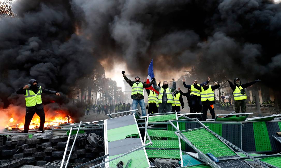 
Descontentamento. Coletes amarelos gritam slogans contra o governo Macron numa barricada improvisada junto ao Arco do Triunfo, na Avenidas dos Champs-Elysées, em Paris: proliferação de grupos a partir de uma petição na internet
Foto: FRANCOIS GUILLOT / FRANCOIS GUILLOT/AFP