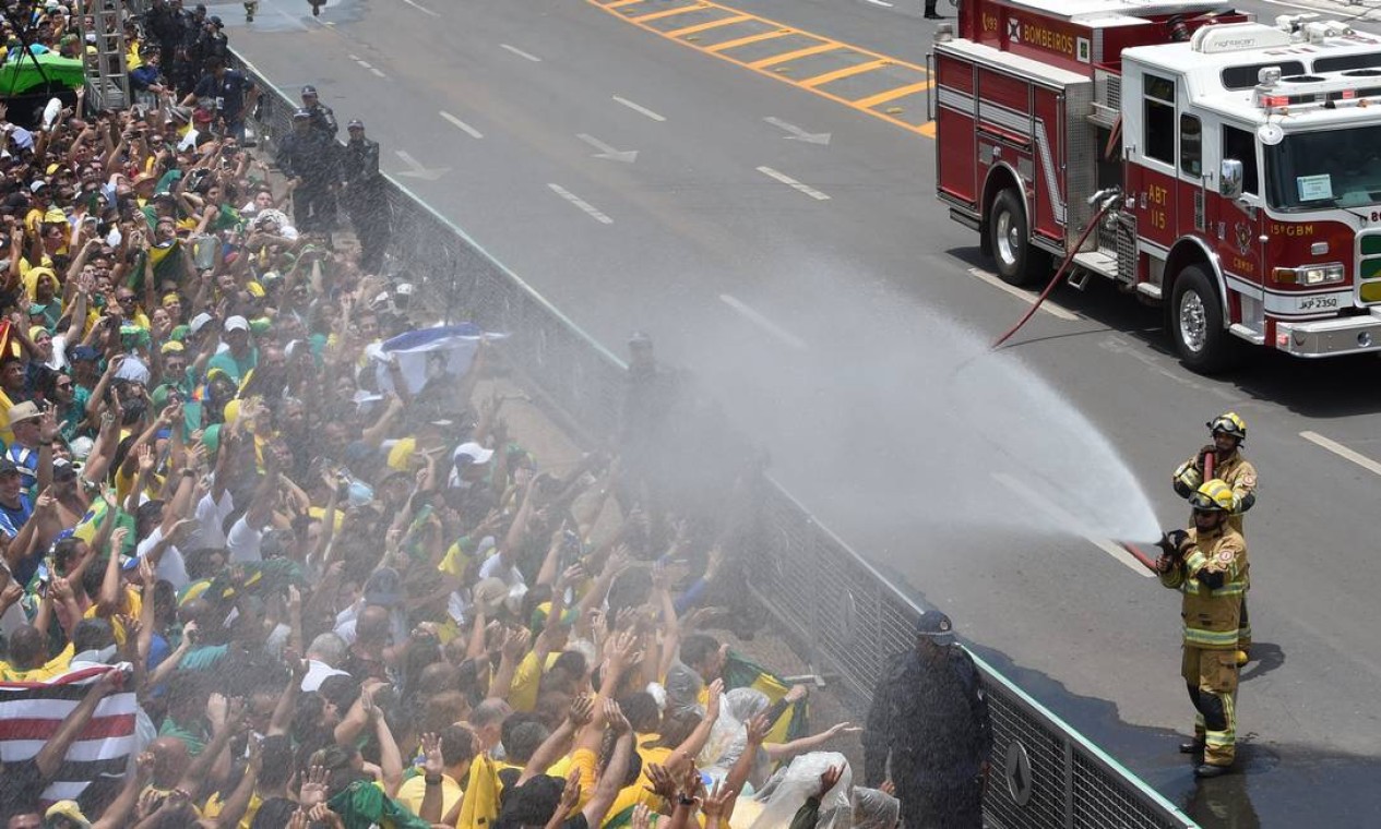 Bombeiros refrescam o público aglomerado para ver a passagem do novo presidente Foto: EVARISTO SA / AFP