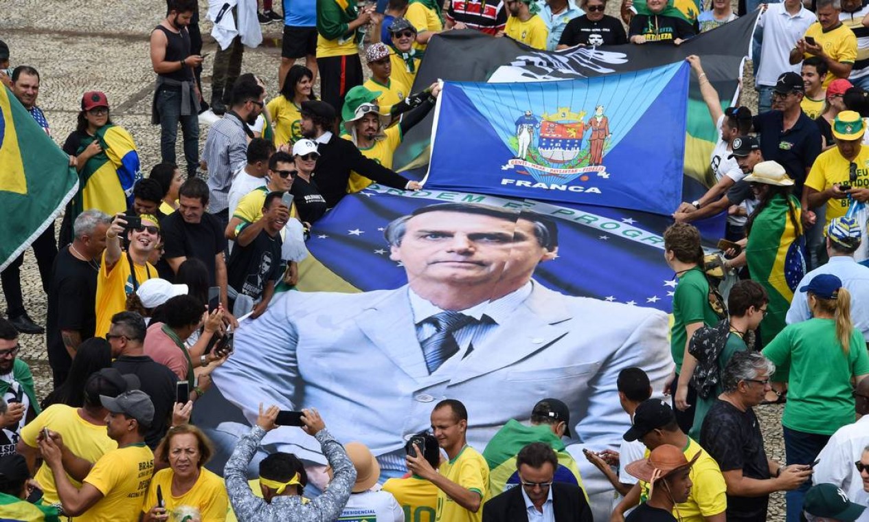 Cartaz com a foto de Bolsonaro é carregado por apoiadores que foram assistir à posse em Brasília Foto: EVARISTO SA / AFP