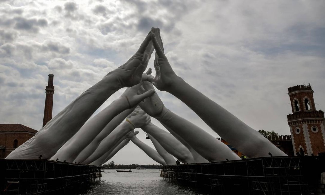 'Building bridges', instalação do iataliano Lorenzo Quinn, na qual seis pares de braços se tocam sobre um canal no Arsenal Foto: TIZIANA FABI / AFP