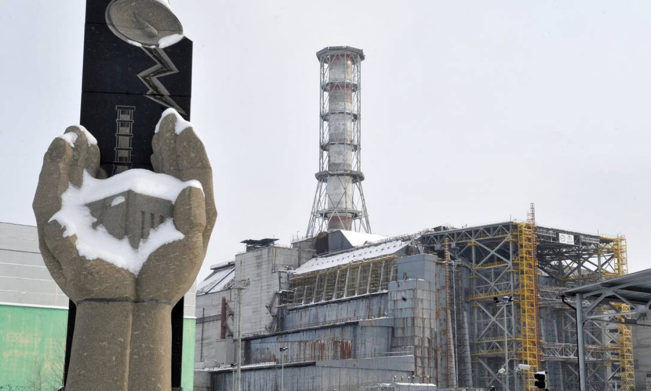 Memorial para as vítimas do desastre de Chernobyl diante do sarcófago da unidade do reator 4 em Chernobyl, em fevereiro de 2011 Foto: SERGEI SUPINSKY / AFP PHOTO