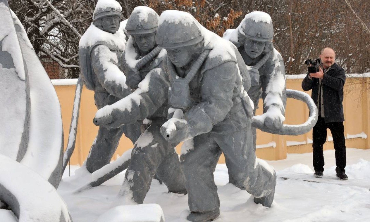 Um visitante fotografa o monumento em homenagem aos bombeiros de Chernobyl em fevereiro de 2011 Foto: SERGEI SUPINSKY / AFP PHOTO