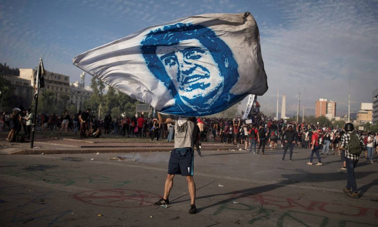 Manifestante agita uma bandeira com a imagem do cantor e compositor chileno Victor Jara, em Santiago, Chile. Canções do artista, torturado e morto pela ditadura do general Augusto Pinochet, viralizaram em meio aos protestos por reforma social que acontecem no país Foto: PABLO SANHUEZA / REUTERS