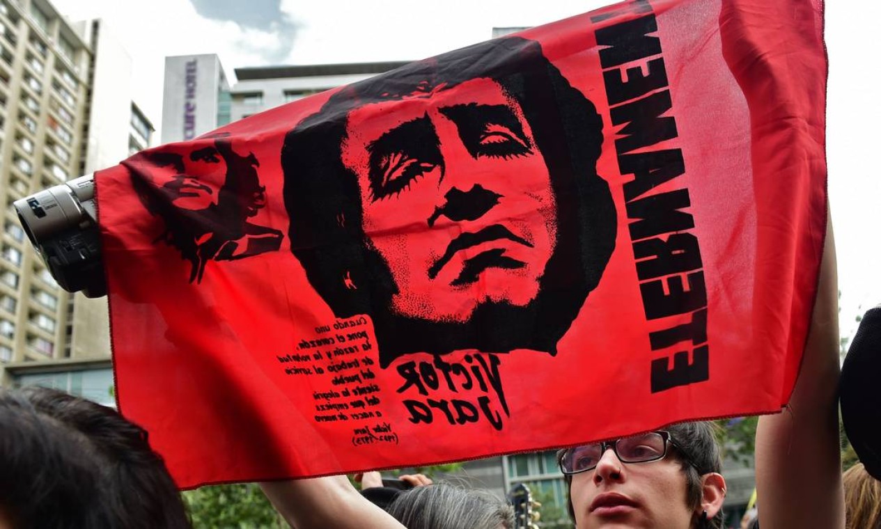 Manifestante segura uma bandeira com imagem do músico chileno Victor Jara durante protesto em 25 de outubro, em Santiago, no Chile. Jara foi detido em 12 de setembro de 1973, após golpe que derrubou o presidente Salvador Allende Foto: MARTIN BERNETTI / AFP