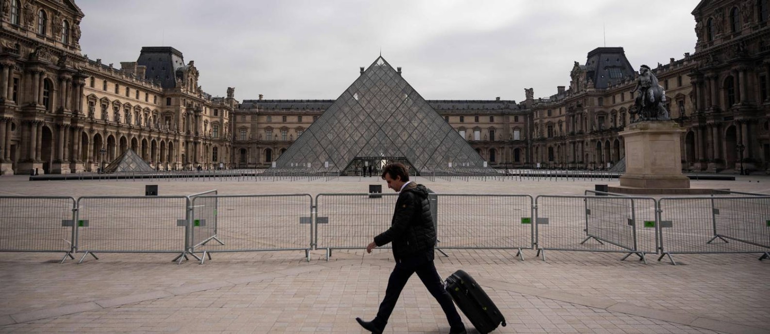 Homem caminha em frente ao Museu do Louvre, em Paris, fechado para visitação pela pandemia de Covid-19 Foto: LIONEL BONAVENTURE / AFP