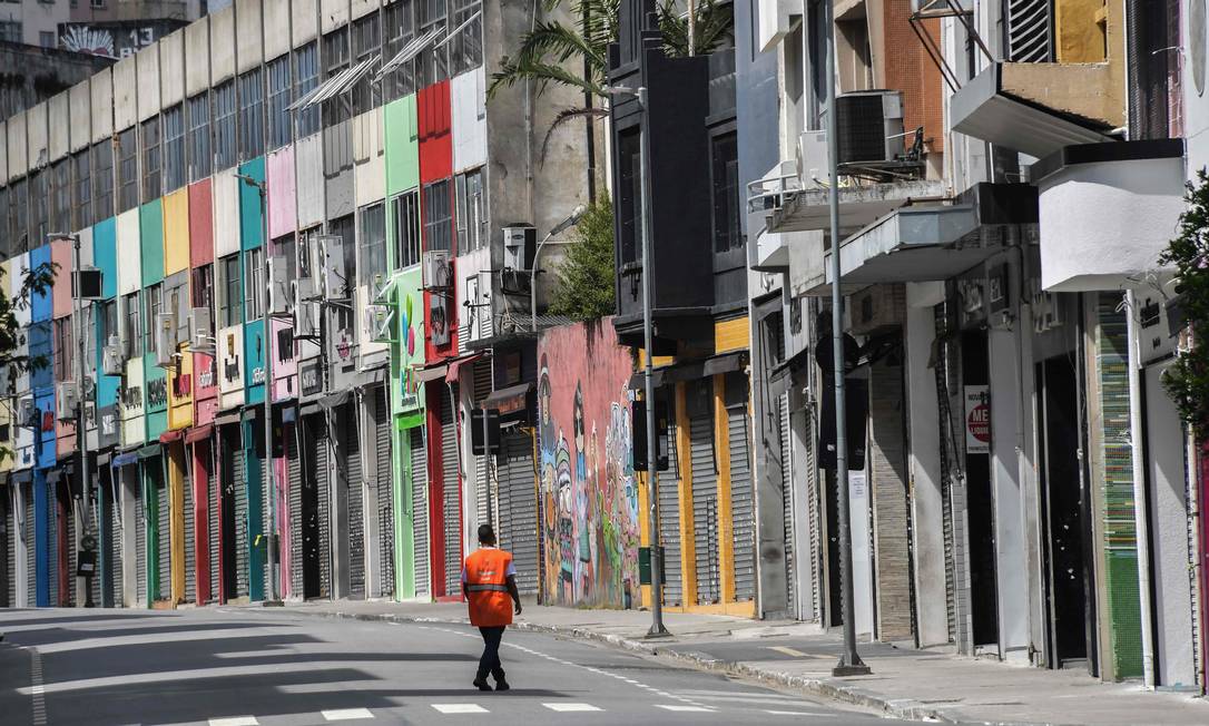 Homem caminha em rua comercial no centro de São Paulo, cidade que ordenou uma quarentena na terça-feira Foto: NELSON ALMEIDA / AFP