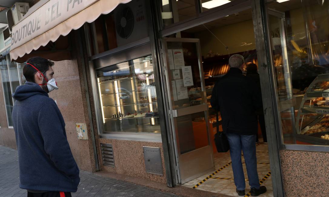 Pessoas praticam distância social enquanto esperam para fazer compras em uma padaria de Madri Foto: SUSANA VERA / REUTERS/29-03-2020