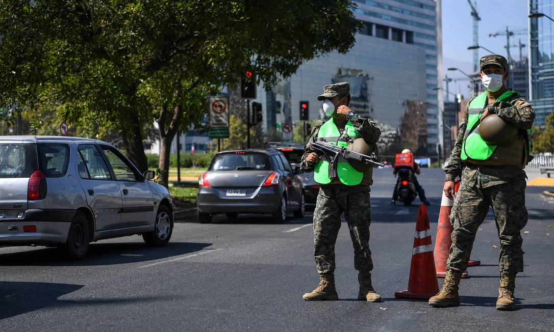 Soldados com máscaras fiscalizam a movimentação de pessoas em Santiago, capital do Chile Foto: MARTIN BERNETTI / AFP