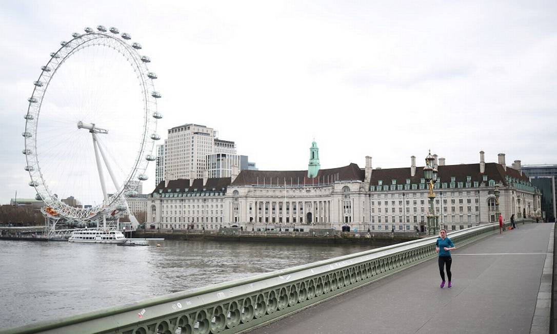 Mulher atravessa a Ponte de Westminster, vazia. Reino Unido liberou 418 bilhões de libras para minorar efeitos da pandemia. Foto: HANNAH MCKAY / REUTERS