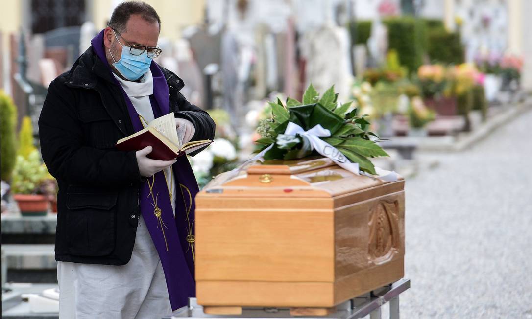 Padre de máscara faz bênçãos diante de caixão, na região da Lombardia, uma das mais afetadas pelo coronavírus na Itália Foto: PIERO CRUCIATTI / AFP