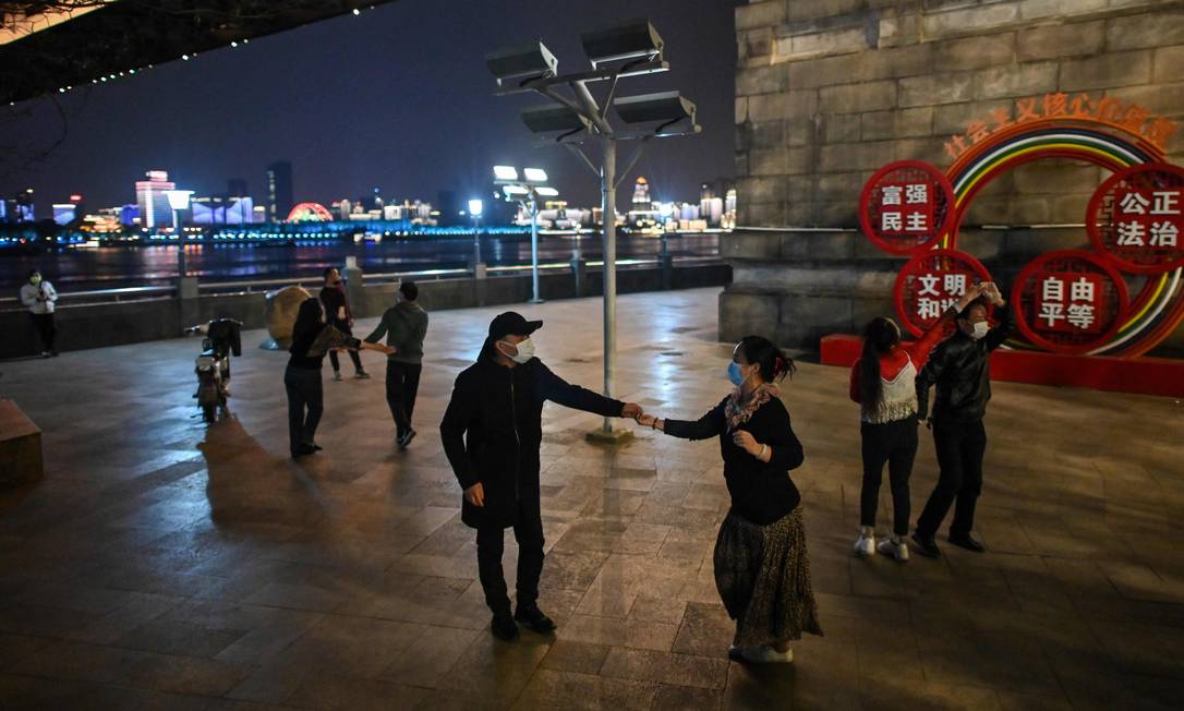 Couples wearing facemasks dance in a park next to the Yangtze River in Wuhan, in China's central Hubei province on April 13, 2020. (Photo by Hector RETAMAL / AFP) Foto: HECTOR RETAMAL / AFP