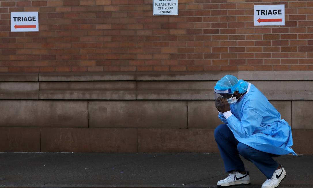 Profissional de saúde descansa em frente a centro médico no Brookly, em Nova York Foto: ANDREW KELLY / REUTERS