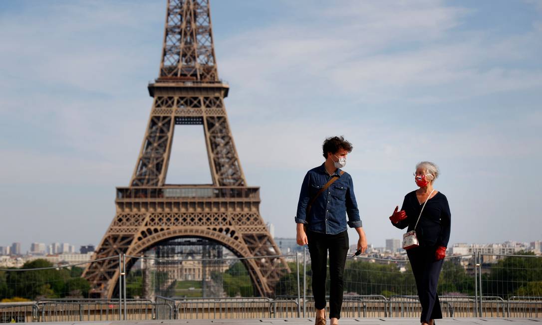 Pessoas com máscara passeiam perto da Torre Eiffel, em Paris Foto: THOMAS COEX / AFP
