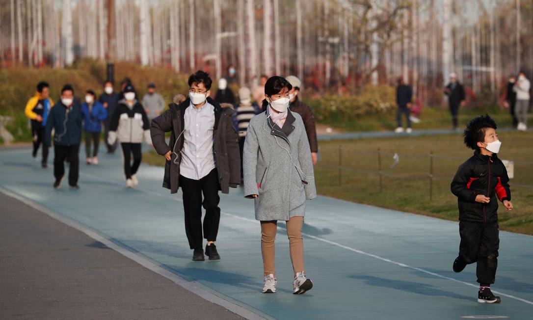 Pessoas usando máscara de prevenção ao coronavírus caminham em um parque de Seul, na Coreia do Sul Foto: KIM HONG-JI / REUTERS/24-04-2020