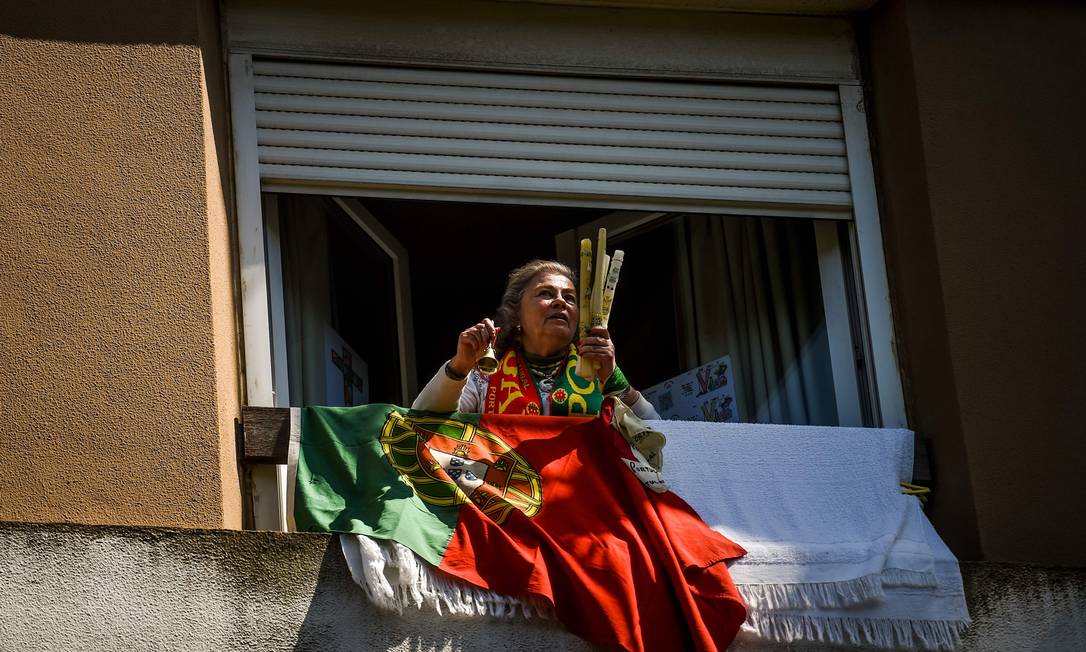 Mulher na janela com a bandeira de Portugal, em Lisboa Foto: PATRICIA DE MELO MOREIRA / AFP