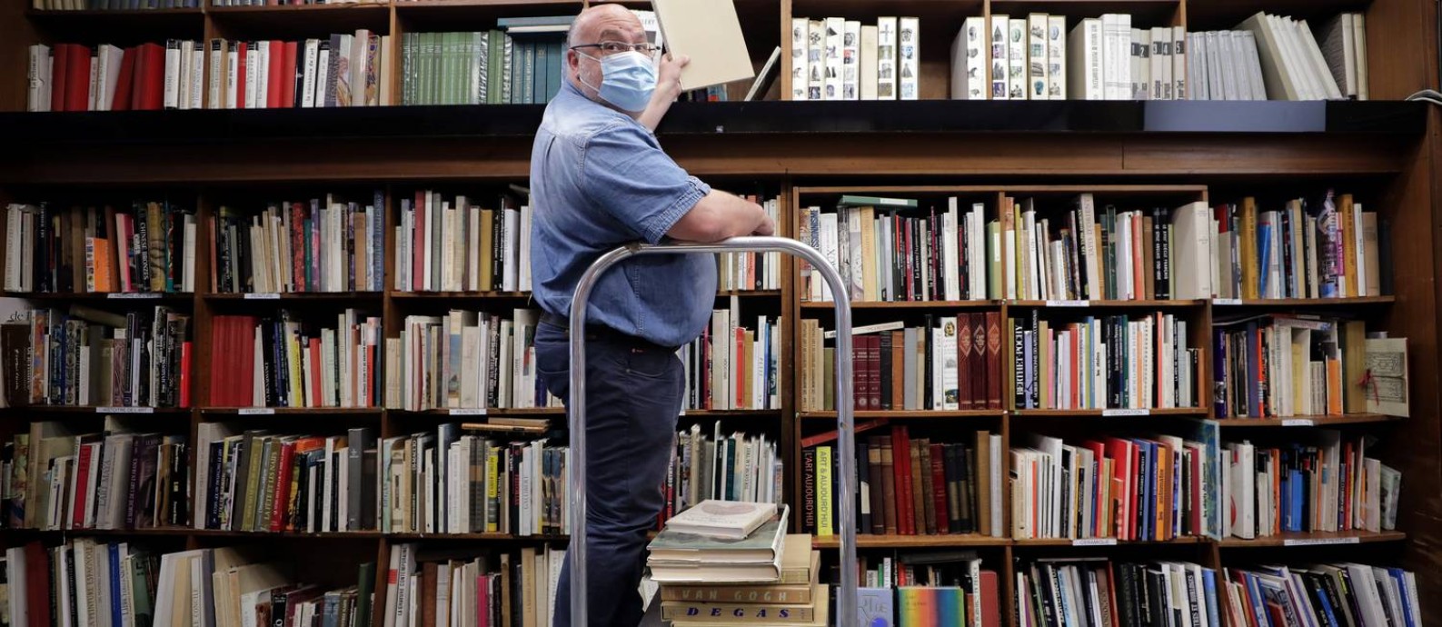 O livreiro Philippe Seyrat usa máscara protetora na livraria La Sorbonne, em Nice, na França, onde o comércio começa a reabrir aos poucos Foto: ERIC GAILLARD / REUTERS