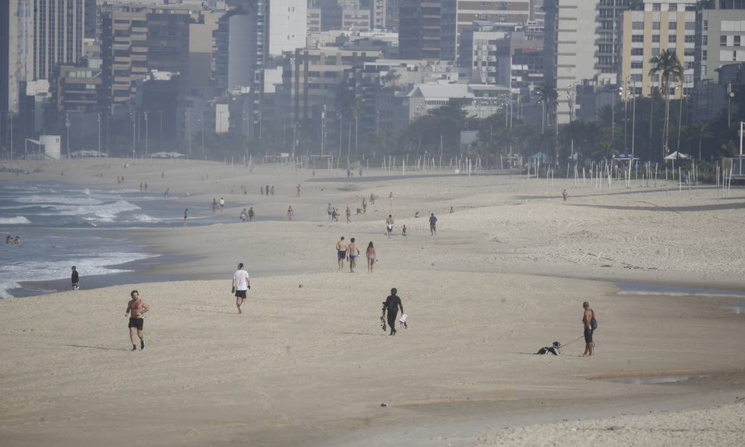 Apesar da suspensão da medidas de flexibilização no Rio, a Praia de Ipanema amanheceu com surfistas na água e pessoas caminhando na areia e no calçadão Foto: Marcia Foletto / Marcia Foletto