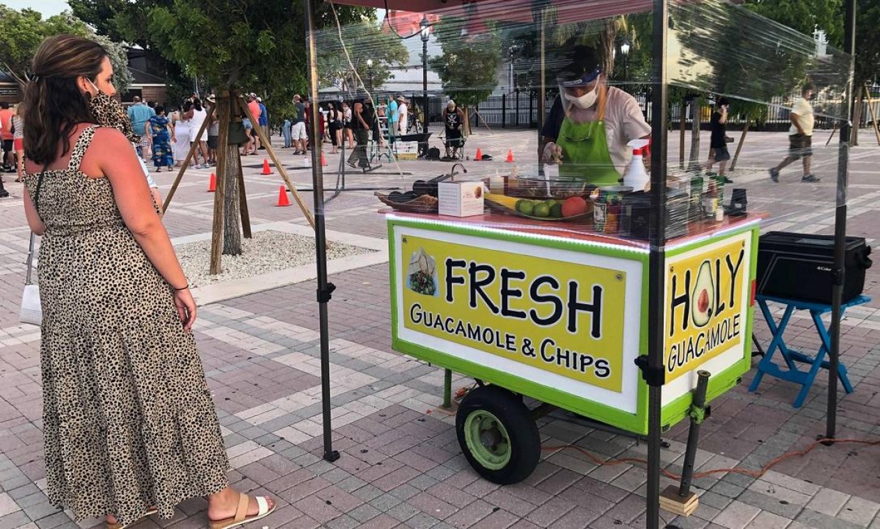 Uma turista espera seu pedido ficar pronto numa carrocinha de guacamole e fritas, equipada com um painel de plástico, em Key West Foto: LEILA MACOR / AFP