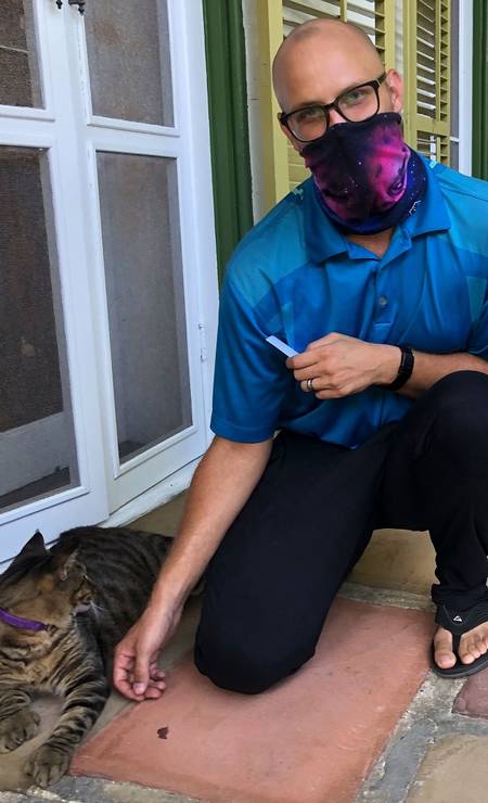 Andrew Morawski, o diretor do the Ernest Hemingway Home and Museum director, faz um carinho em Joe DiMaggio, um dos gatos de seis dedos que vivem na casa-museu do escritor em Key West, na Flórida Foto: LEILA MACOR / AFP