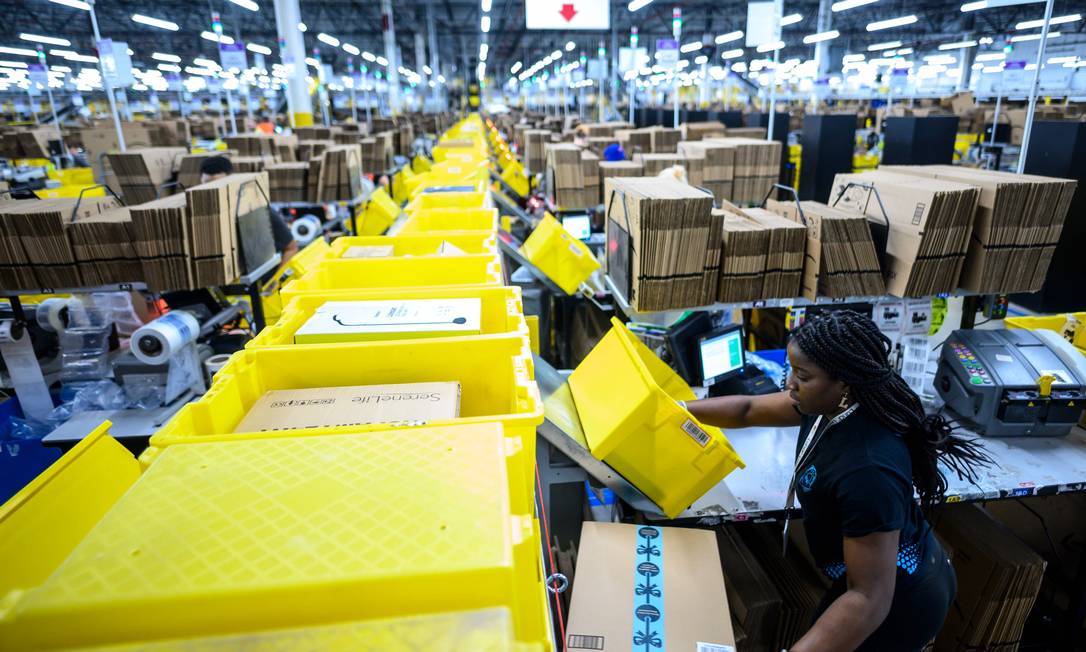 Nos depósitos da Amazon, "os livros estão guardados ao lado de torradeiras, brinquedos ou skates", escreve Jordi Carrión no livro "Contra a Amazon". Na foto, funcionários preparam encomendas em um depósito da empresa americana em Nova York Foto: JOHANNES EISELE / AFP