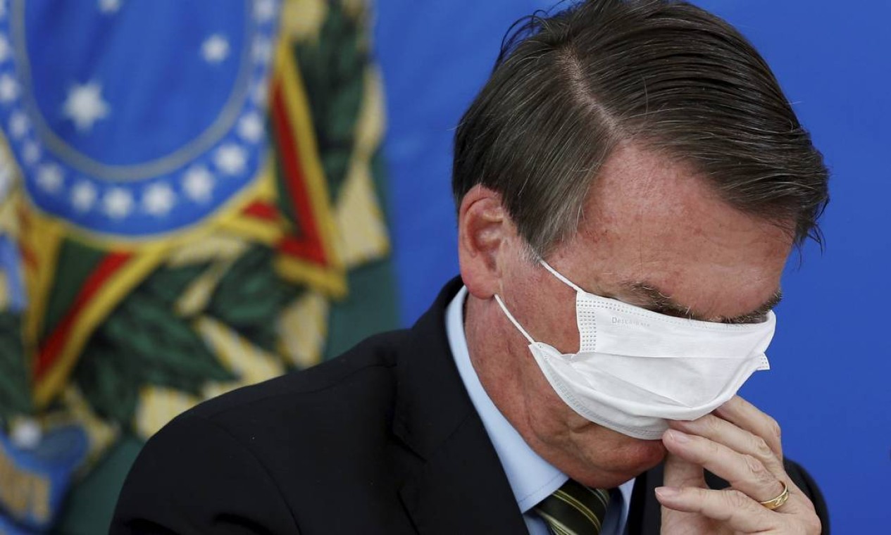 Tapando os olhos. O presidente Bolsonaro se atrapalha com a máscara de proteção durante o anúncio, em março, das primeiras medidas do governo para o combate à pandemia Foto: Pablo Jacob / Agência O Globo - 18/03/2020