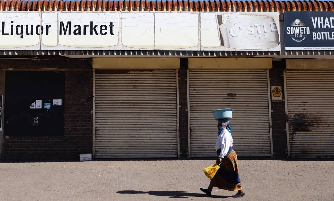 Mulher caminha em frente a loja de bebidas fechada em Soweto, na África do Sul Foto: MICHELE SPATARI / AFP/13-07-2020
