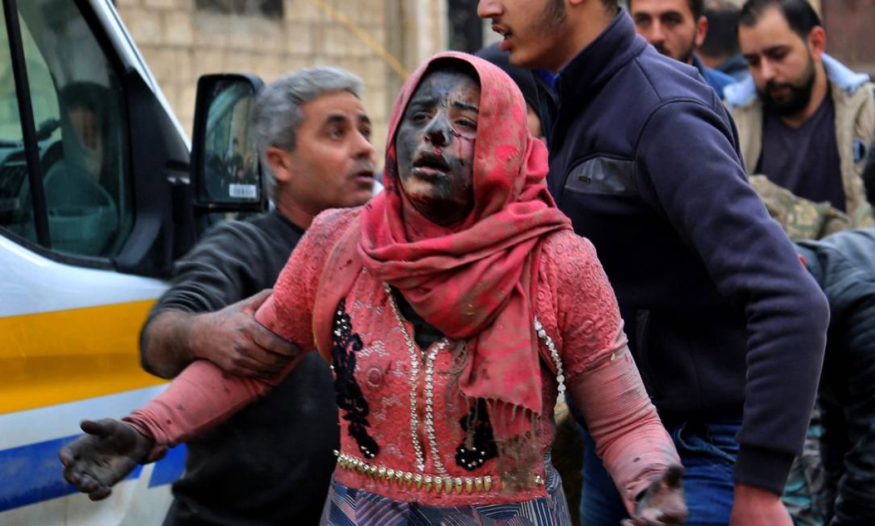 Homens sírios ajudam uma mulher ferida coberta de poeira após um ataque na cidade de Khan Shaykhun, no interior do sul da província de Idlib, controlada pelos rebeldes Foto: ANAS AL-DYAB / AFP - 15/02/2019