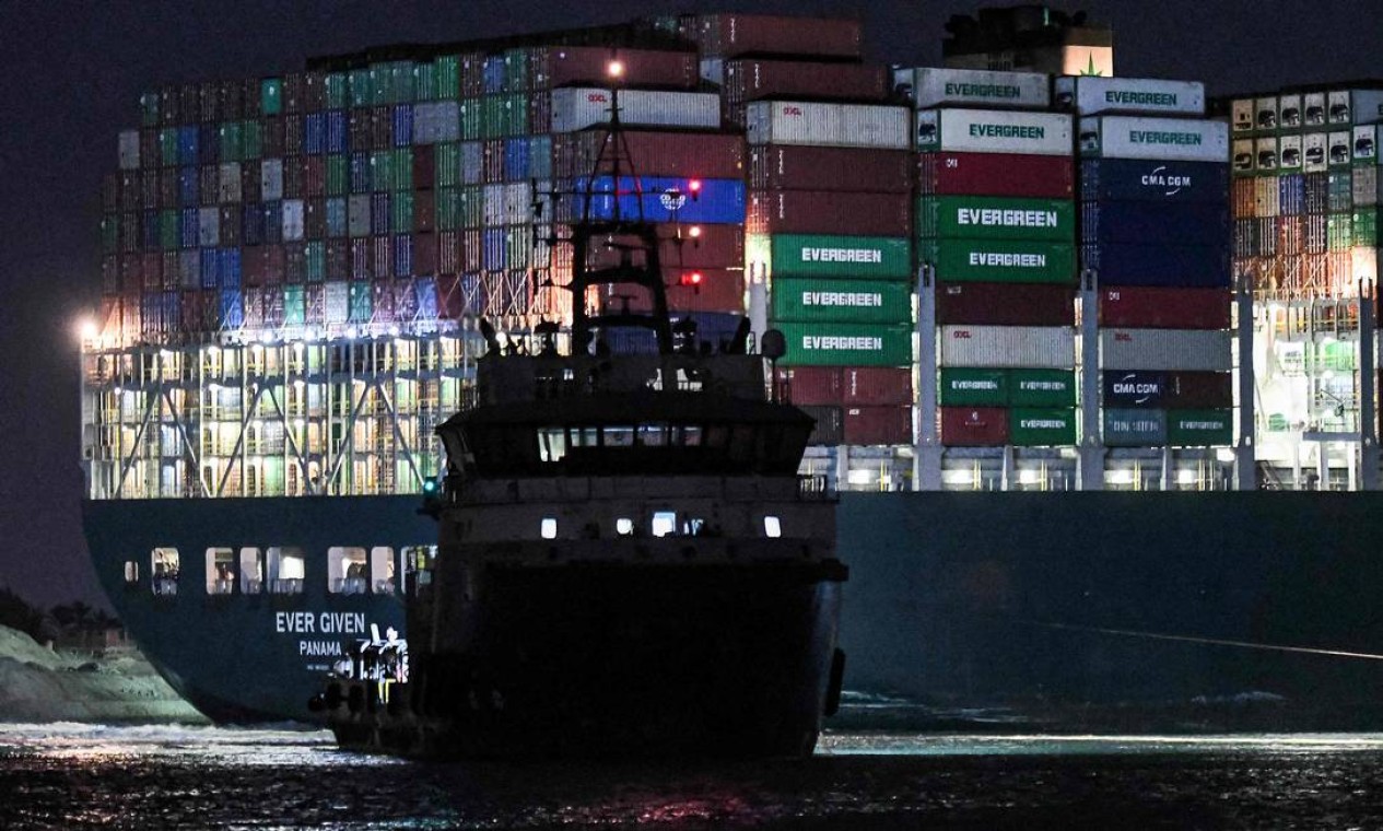 Rebocador trabalha durante a noite para desencalhar navio cargueiro gigante Foto: AHMED HASAN / AFP