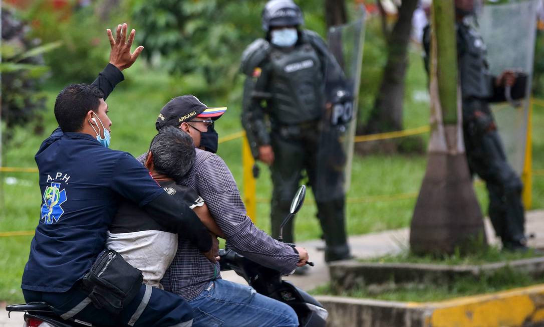 Um manifestante ferido é levado em uma motocicleta por outros homens durante confrontos com a polícia em protesto em Cali, Colômbia Foto: PAOLA MAFLA / AFP