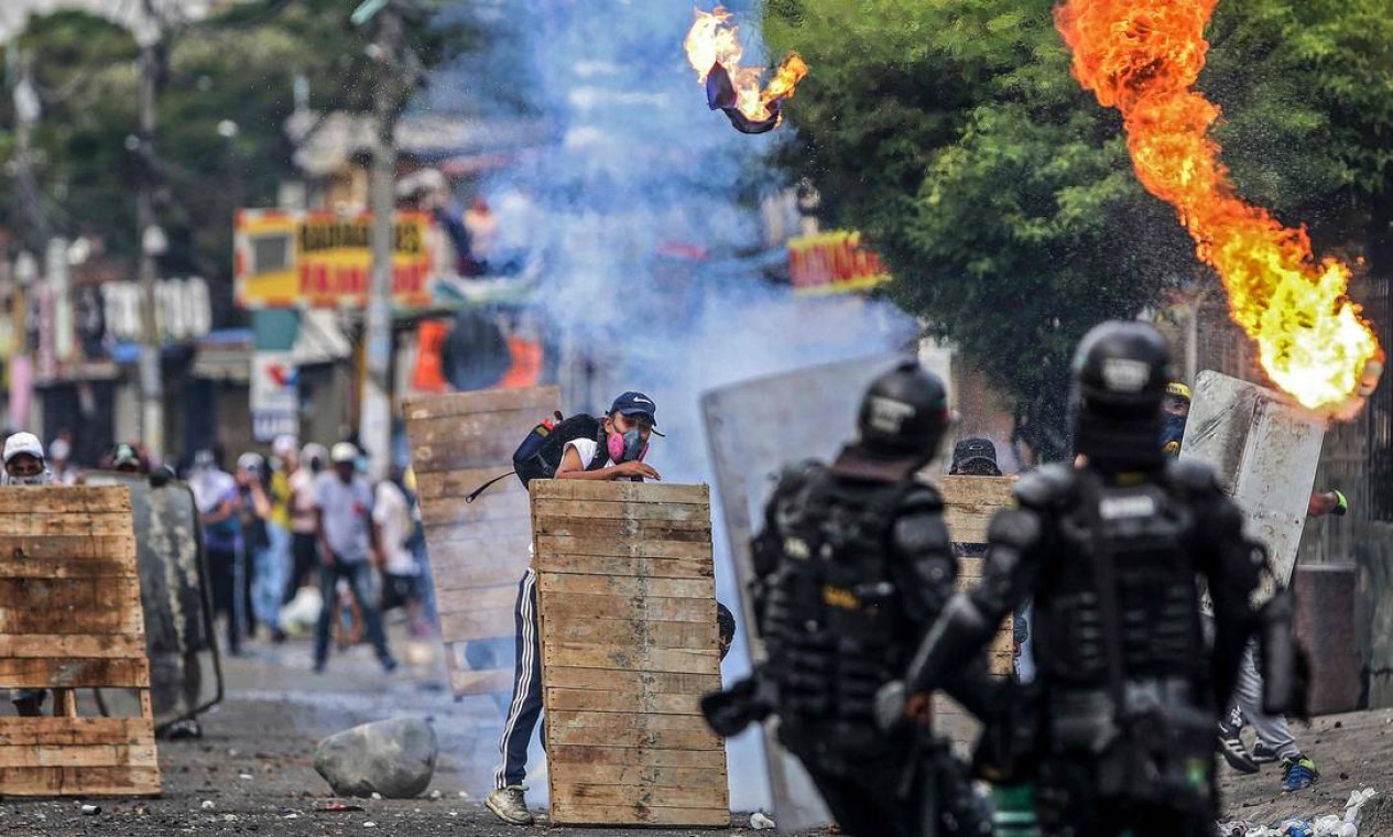 Manifestantes enfrentam tropas de choque durante protesto contra projeto de reforma tributária lançado pelo presidente colombiano Ivan Duque, em Cali Foto: PAOLA MAFLA / AFP