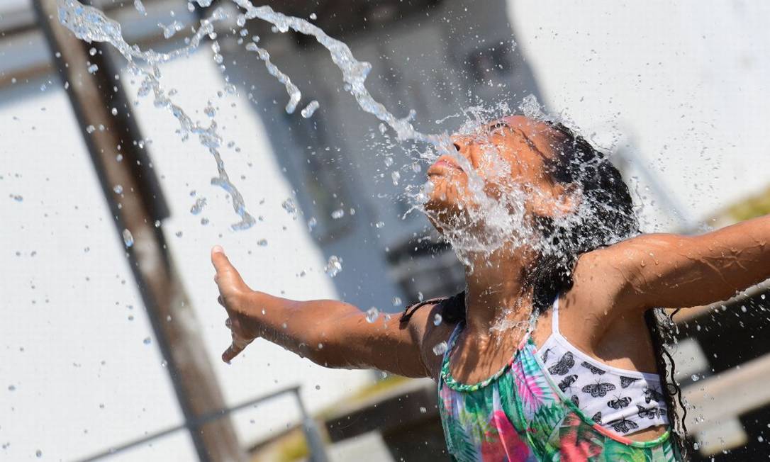 Criança se refresca em fonte de água em Richmond, na Columbia Britânica, no Canadá Foto: DON MACKINNON / AFP