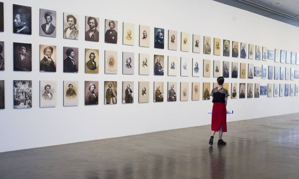 Mulher junto a fotos do abolicionista Frederick Douglass (1818-1895), que se retratava como foram de lutar contra
a invisibilização Foto: Edilson Dantas / Agência O Globo