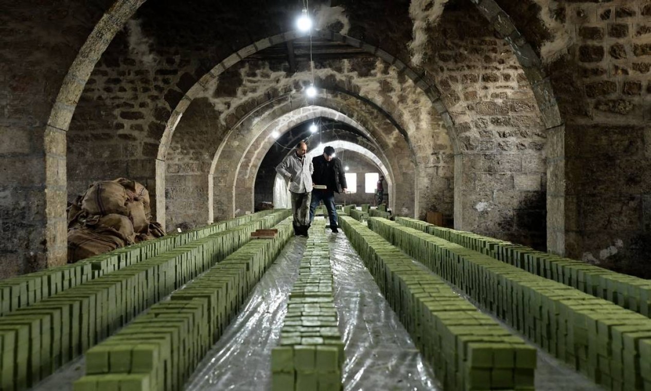 Trabalhadores sírios inspecionam pilhas de sabão de louro na fábrica de sabão Jbaili, produzido artesanalmente há de 800 anos, em Aleppo, no norte da Síria. A produção foi retomada depois que as forças do governo sírio retomaram a cidade velha Foto: - / AFP