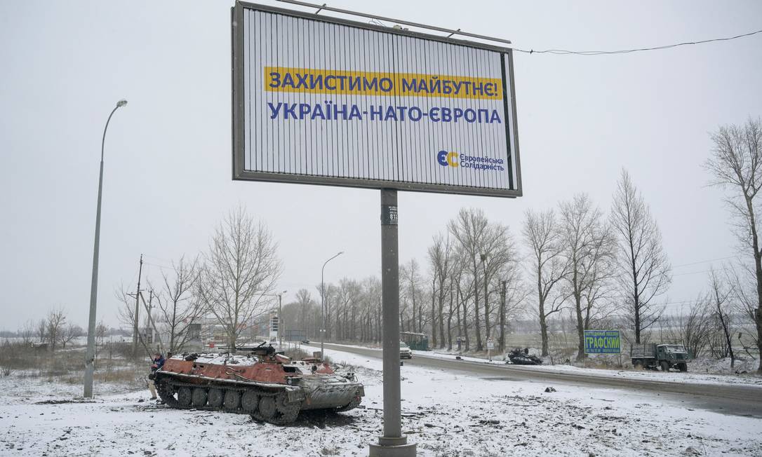 Veículo militar destruído em estrada nos arredores de Kharkiv. A placa diz "Vamos proteger o futuro: Ucrânia-Otan-Europa" Foto: MAKSIM LEVIN / REUTERS