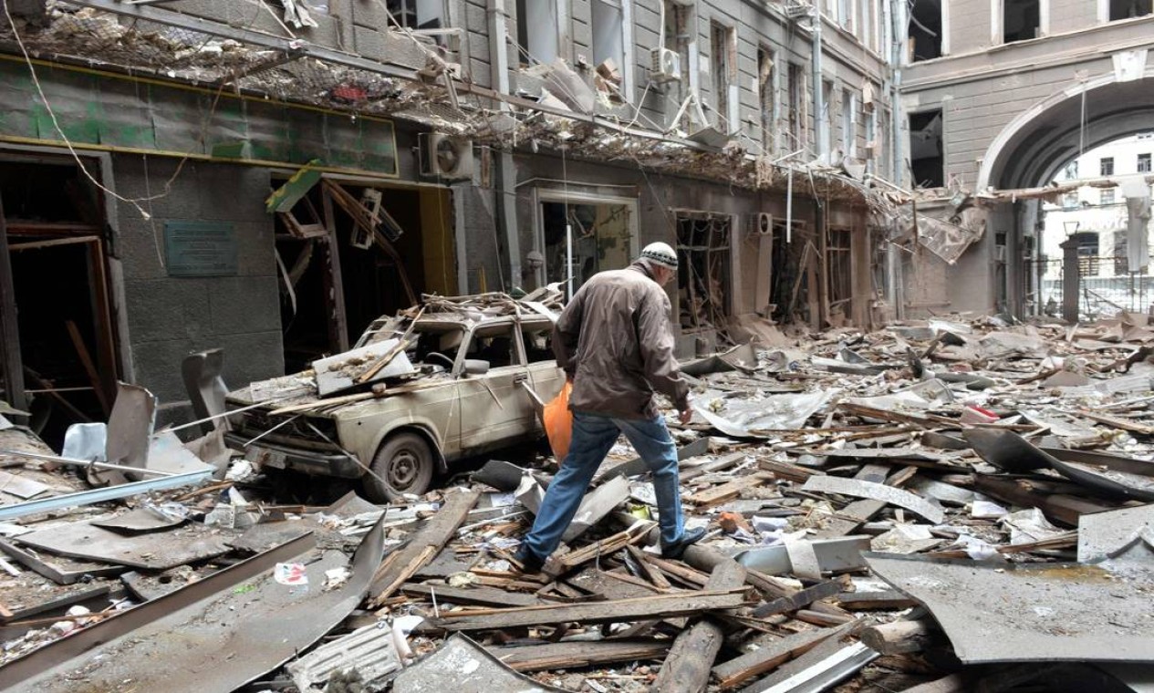 Homem caminha sobre escombros de prédio danificado após o bombardeio russo na segunda maior cidade da Ucrânia, Kharkiv Foto: SERGEY BOBOK / AFP