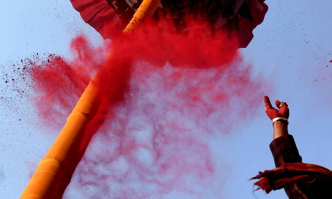 Cevoto joga pó colorido em direção ao poste de bambu cerimonial conhecido como 'Chir', franjado com tiras de pano representando amuletos de boa sorte, para marcar o início do Holi, o festival de cores da primavera, na Praça Basantapur Durbar, em Katmandu, Nepal Foto: PRAKASH MATHEMA / AFP