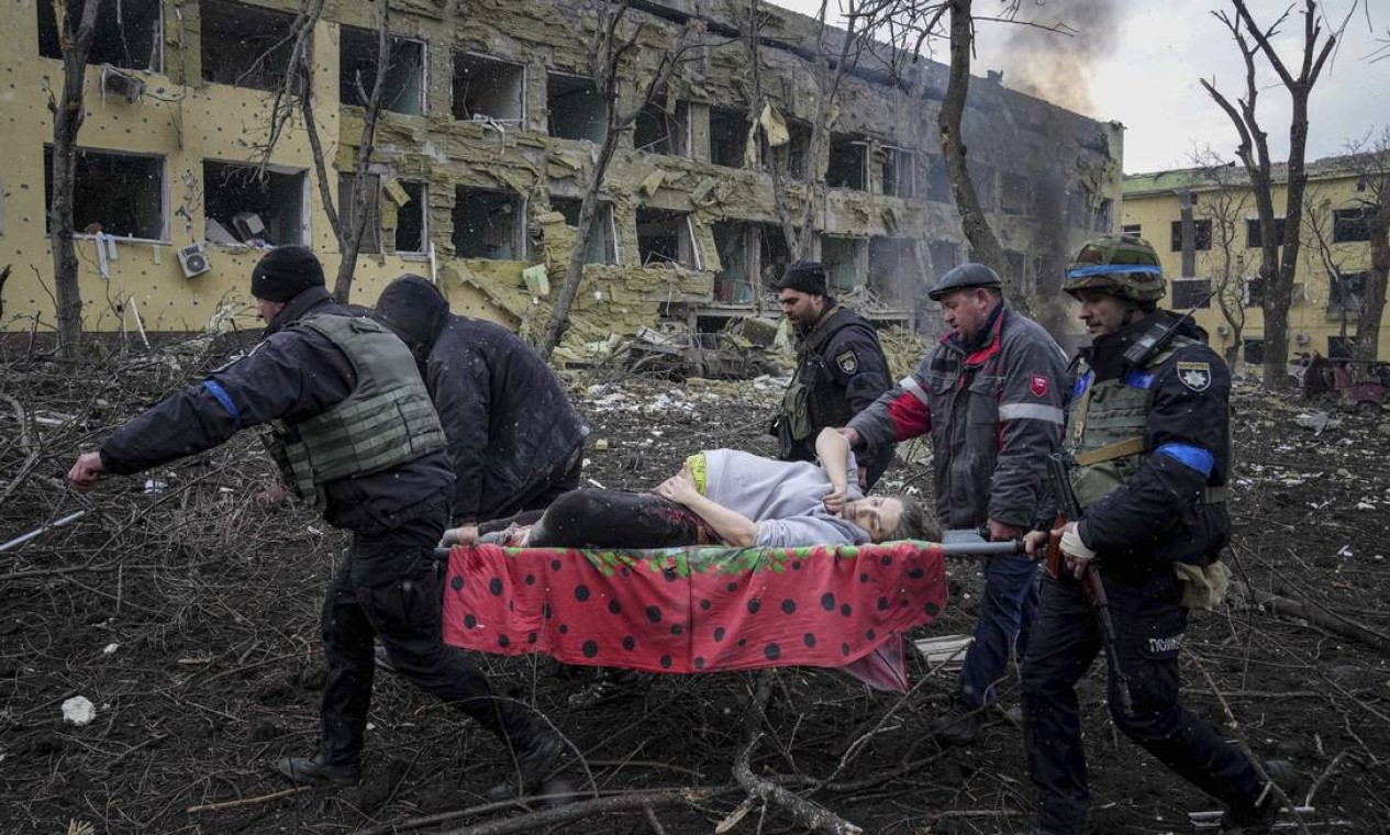 Funcionários e voluntários de emergência ucranianos carregam uma mulher grávida ferida da maternidade em Mariupol, na Ucrânia Foto: EVGENIY MALOLETKA/AP / Agência O Globo