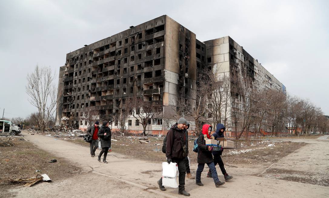 Pessoas caminham por ruas destruídas em Mariupol, Ucrânia, durante conflito com a Rússia Foto: ALEXANDER ERMOCHENKO / REUTERS