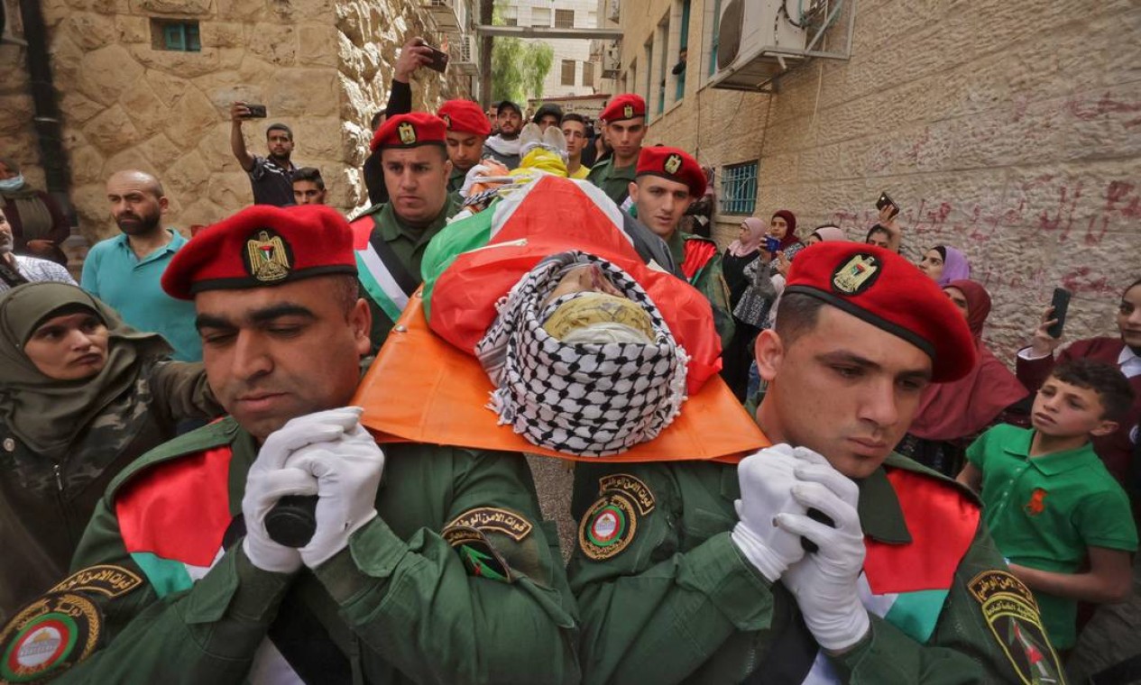 Oficiais de segurança palestinos carregam o corpo de Mohammed Ghnaim durante seu funeral na vila de al-Khader, perto da cidade de Belém, na Cisjordânia ocupada. Jovem foi morto a tiros pelo exército israelense Foto: HAZEM BADER / AFP