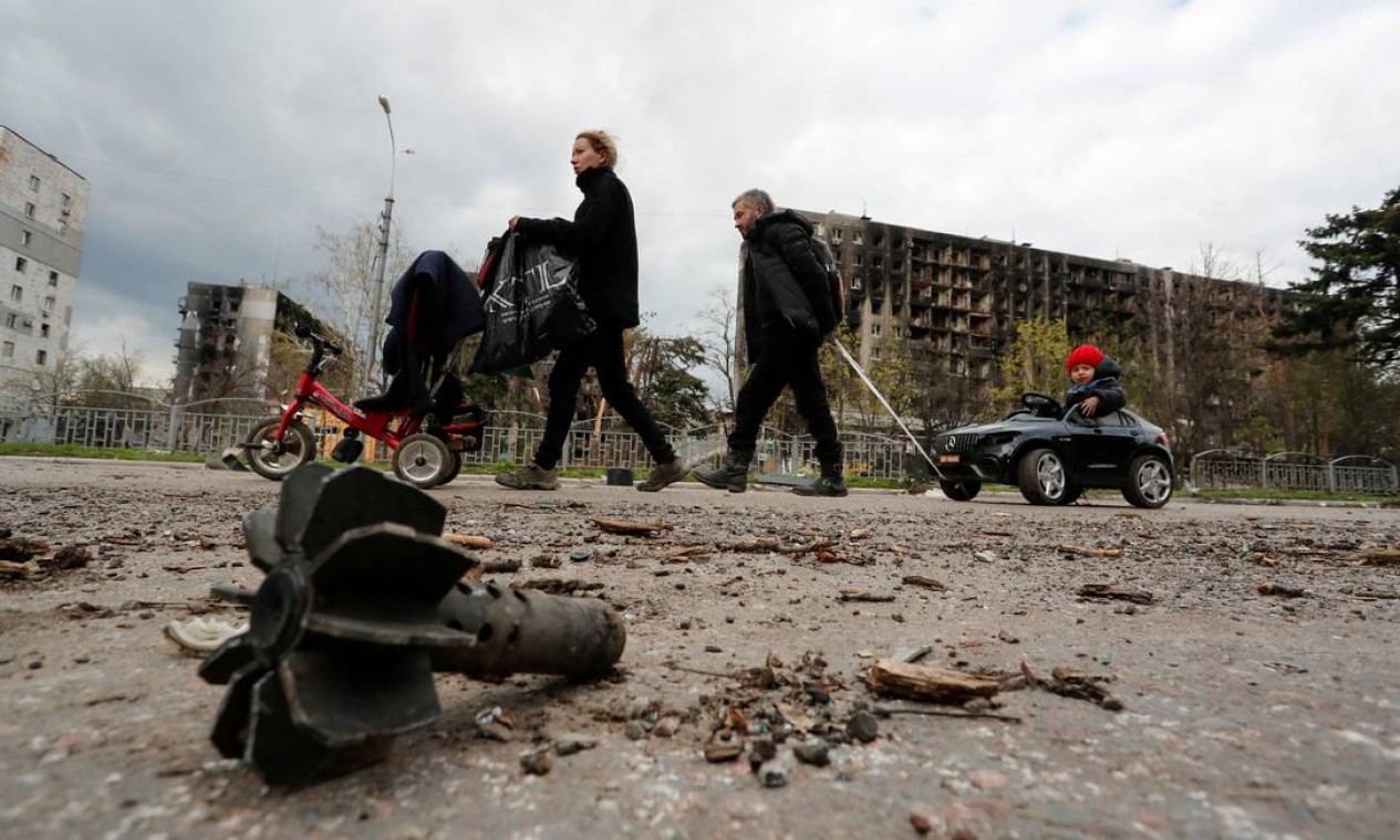 Familiares caminham perto de prédios danificados durante o conflito Ucrânia-Rússia na cidade portuária de Mariupol, no sul da Ucrânia Foto: ALEXANDER ERMOCHENKO / REUTERS